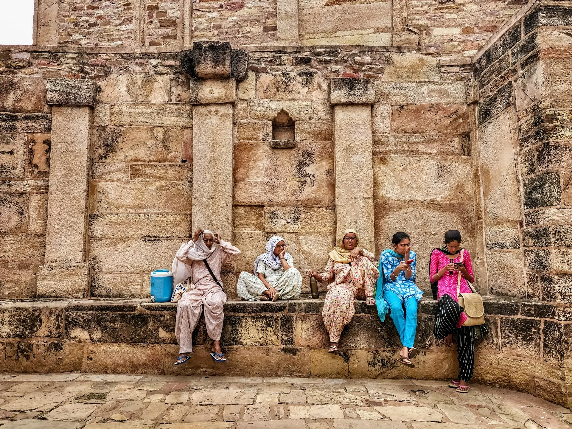 a group of people sitting next to each other on a stone wall